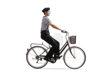 Téléchargez les photos : Photo de profil pleine longueur d'un mime chevauchant un vélo isolé sur fond blanc - en image libre de droit