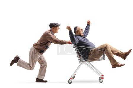 Téléchargez les photos : Senior homme poussant un ami à l'intérieur d'un panier isolé sur fond blanc - en image libre de droit