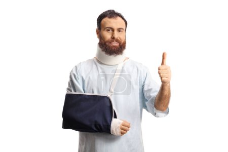 Photo for Bearded male patient with and arm sling and cervical collar gesturing thumbs up isolated on white background - Royalty Free Image
