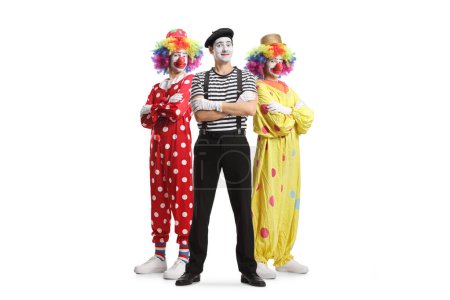 Téléchargez les photos : Portrait complet de deux clowns et un mime posant avec les bras croisés isolés sur fond blanc - en image libre de droit