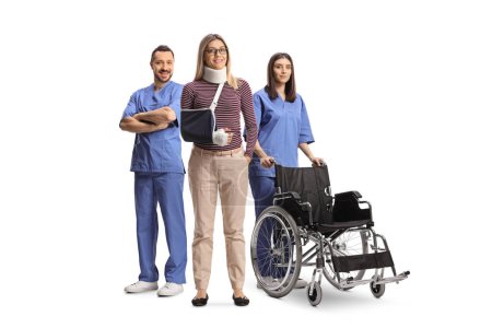 Foto de Paciente femenina con un brazo y cuello rotos de pie con trabajadores de la salud aislados sobre fondo blanco - Imagen libre de derechos