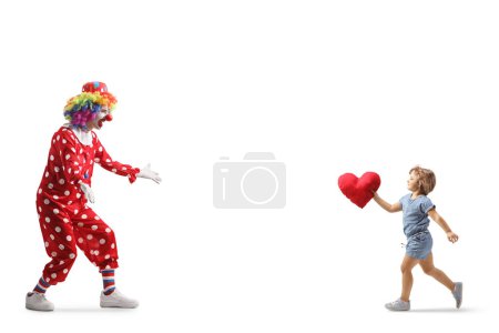 Téléchargez les photos : Plan complet d'une petite fille portant un cœur et courant embrasser un clown isolé sur fond blanc - en image libre de droit