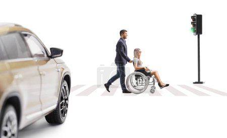 Photo for Full length profile shot of a young man pushing a young woman in a wheelchair at a pedestrian crossing isolated on white background - Royalty Free Image