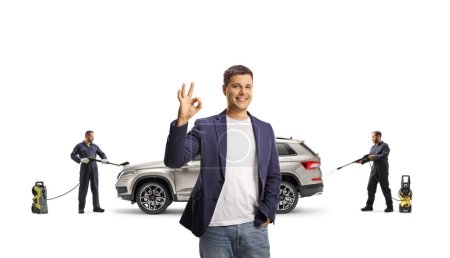 Photo for Male customer gesturing ok sign and car wash workers in cleaning a SUV with a pressure washer machines isolated on white background - Royalty Free Image