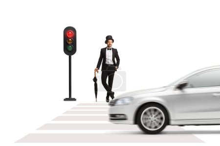 Photo for Full length portrait of a young gentleman with a top hat and umbrella waiting at traffic lights isolated on white background - Royalty Free Image