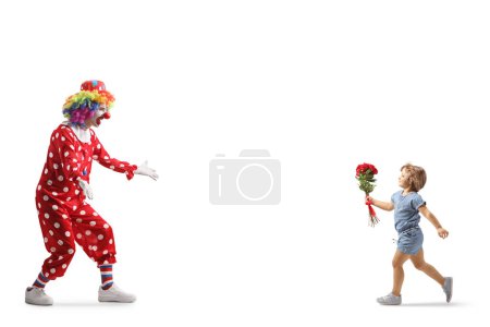 Téléchargez les photos : Plan complet d'une petite fille portant des fleurs et courant embrasser un clown isolé sur fond blanc - en image libre de droit