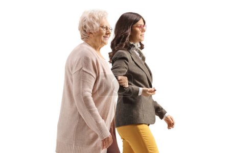 Foto de Mujer anciana sosteniendo a una mujer joven bajo el brazo y caminando aislada sobre fondo blanco - Imagen libre de derechos