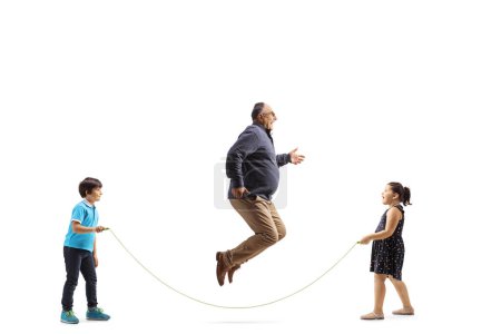 Téléchargez les photos : Plan de profil complet d'un homme mature sautant une corde avec des enfants isolés sur fond blanc - en image libre de droit