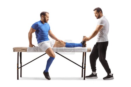 Téléchargez les photos : Physiothérapeute traitant un joueur de football isolé sur fond blanc - en image libre de droit