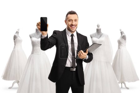 Téléchargez les photos : Homme d'affaires avec documents montrant un téléphone portable dans un magasin de mariage isolé sur fond blanc - en image libre de droit
