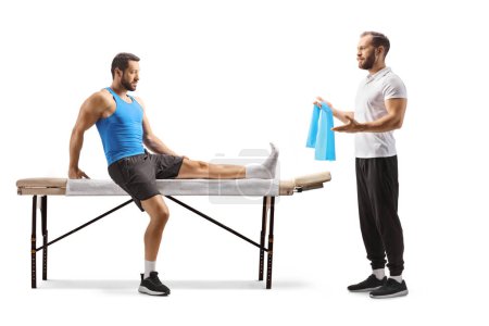Téléchargez les photos : Physiothérapeute montrant l'exercice à un athlète masculin avec une jambe blessée isolé sur fond blanc - en image libre de droit