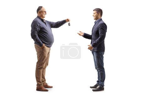 Photo for Mature man handing car keys to a younger man isolated on white background - Royalty Free Image