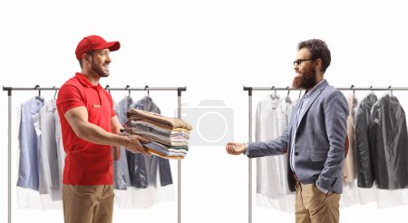 Photo for Man giving a pile of dry cleaning clothes to a male customer isolated on a white backgroun - Royalty Free Image