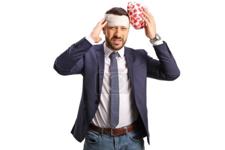 Téléchargez les photos : Homme avec une blessure à la tête portant un bandage et tenant la banquise pour le mal de tête isolé sur fond blanc - en image libre de droit