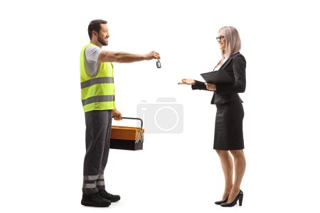 Photo for Full length profile shot of a road assistance agent in a reflective vest giving a car key to a woman isolated on white background - Royalty Free Image