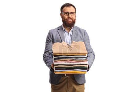 Photo for Bearded man holding a pile of folded clothes and smiling at camera isolated on a white background - Royalty Free Image