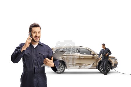 Photo for Carswash workers with a pressure washer cleaning a SUV and using a smartphone isolated on white background - Royalty Free Image