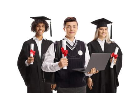 Téléchargez les photos : Écolier avec un ordinateur portable posant avec des étudiants diplômés isolés sur fond blanc - en image libre de droit