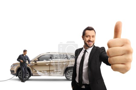 Carswash worker with a pressure washer cleaning a SUV and a businessman gesturing thumbs up isolated on white background