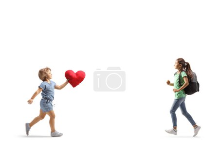 Téléchargez les photos : Petite fille portant un cœur rouge et courant à la rencontre d'une étudiante isolée sur fond blanc - en image libre de droit