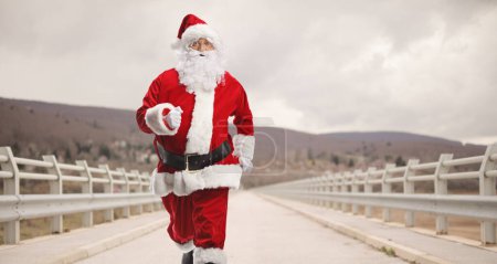 Foto de Santa Claus corriendo por un puente en un día nublado - Imagen libre de derechos