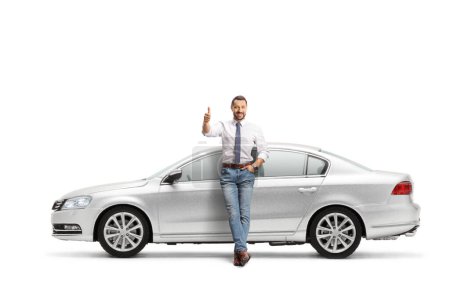 Photo for Full length portrait of a man leaning on a silver car and gesturing thumbs up isolated on white background - Royalty Free Image