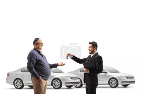 Foto de Vendedor de coches dando llaves a un hombre maduro aislado sobre fondo blanco - Imagen libre de derechos