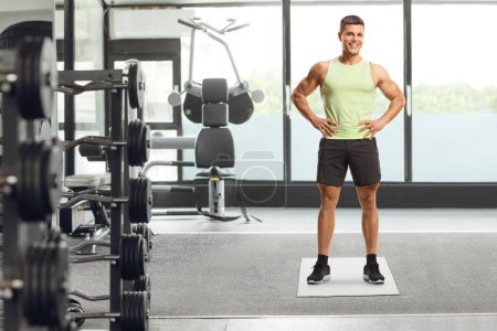 Photo for Fit young man in sportswear smiling at camera and posing at a gym - Royalty Free Image