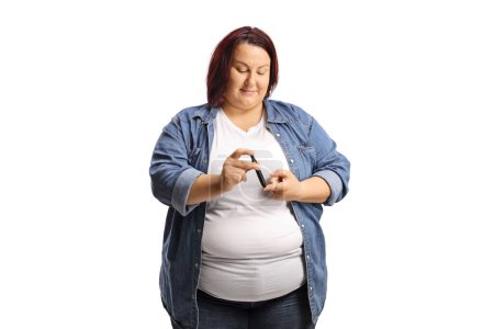 Foto de Mujer joven con sobrepeso usando una pluma de insulina en el dedo aislada sobre fondo blanco - Imagen libre de derechos