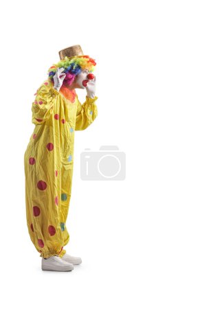 Photo for Clown in a yellow costume holding his wig isolated on white background - Royalty Free Image