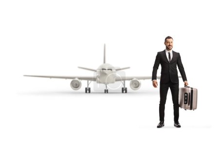 Téléchargez les photos : Portrait complet d'un homme en costume et cravate portant une valise devant un avion isolé sur fond blanc - en image libre de droit
