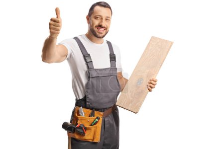 Téléchargez les photos : Charpentier tenant une poutre de plancher en bois et geste d'un pouce vers le haut signe isolé sur fond blanc - en image libre de droit