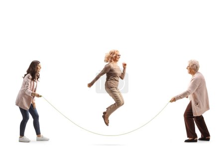 Foto de Mujeres jóvenes y mayores jugando a saltar la cuerda aisladas sobre fondo blanco - Imagen libre de derechos