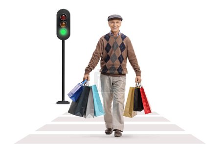 Photo for Full length portrait of an elderly man carrying shopping bags and walking at a pedestrian crosswalk isolated on white background - Royalty Free Image