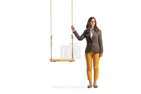 Téléchargez les photos : Portrait complet d'une jeune femelle debout à côté d'une balançoire en bois vide isolée sur fond blanc - en image libre de droit
