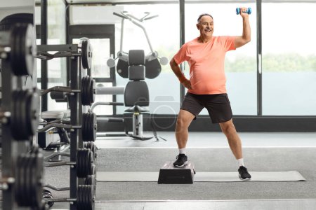Photo for Mature man exercising step aerobic at a gym - Royalty Free Image