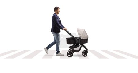 Photo for Full length profile shot of a father with a pushchair walking at a pedestrian crossing isolated on white background - Royalty Free Image