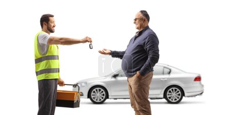 Foto de Trabajador mecánico dando llaves de coche a un hombre maduro aislado sobre fondo blanco - Imagen libre de derechos