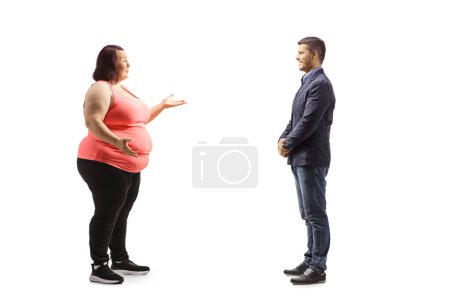 Photo for Full length profile shot of an overweight young woman in sportswear talking to a man isolated on white background - Royalty Free Image