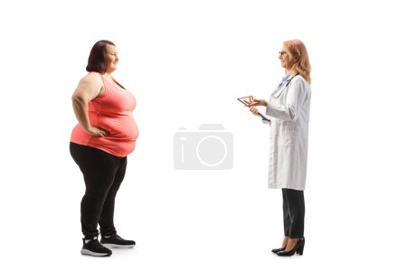 Foto de Foto de perfil completo de un médico hablando con una mujer joven con sobrepeso aislada sobre fondo blanco - Imagen libre de derechos