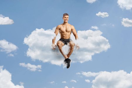 Foto de Fisicoculturista sin camisa sentado en una nube en el cielo - Imagen libre de derechos