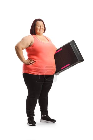 Téléchargez les photos : Plan complet d'une femme corpulente tenant une plate-forme aérobie d'étape isolée sur fond blanc - en image libre de droit