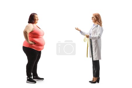 Foto de Foto de perfil completo de un nutricionista hablando con una joven con sobrepeso en ropa deportiva aislada sobre fondo blanco - Imagen libre de derechos