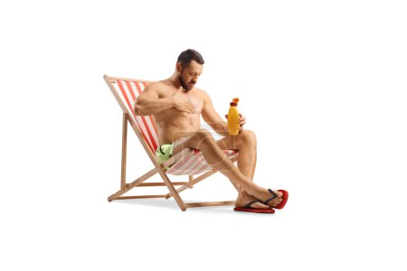 Photo for Man sitting on a deck chair and putting on sun cream isolated on white background - Royalty Free Image