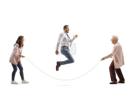 Téléchargez les photos : Jeune homme et femme jouant corde à sauter avec une femme âgée isolée sur fond blanc - en image libre de droit