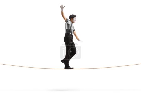 Téléchargez les photos : Plan de profil complet d'un mime marchant sur une corde raide isolée sur fond blanc - en image libre de droit