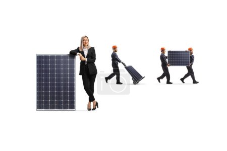 Foto de Mujer gerente de pie junto a un panel solar y los trabajadores que llevan paneles en la parte posterior aislado sobre fondo blanco - Imagen libre de derechos