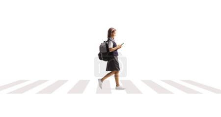 Photo for Schoolgirl crossing a street and using a smartphone isolated on white background - Royalty Free Image