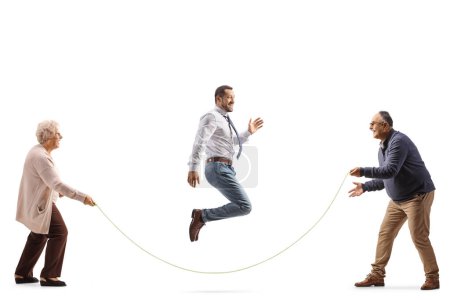 Téléchargez les photos : Senior homme et femme tenant une corde et jeune homme sautant isolé sur fond blanc - en image libre de droit
