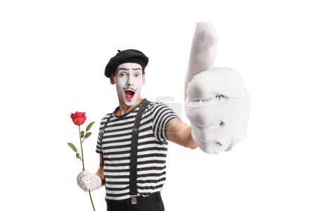 Téléchargez les photos : Mime tenant une rose rouge et montrant les pouces isolés sur fond blanc - en image libre de droit